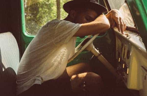 Foto de um homem dentro de uma caminhonete, apoiado no volante, dormindo. Cansado devido à ansiedade.