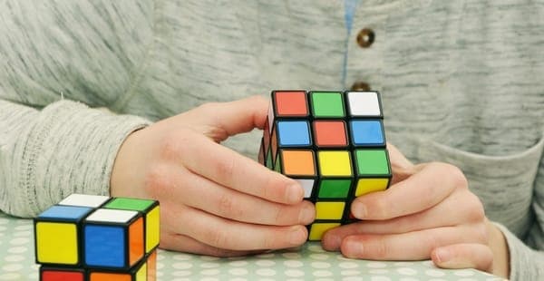 Foto de uma pessoa tentando resolver um cubo mágico, atividade que exige concentração.